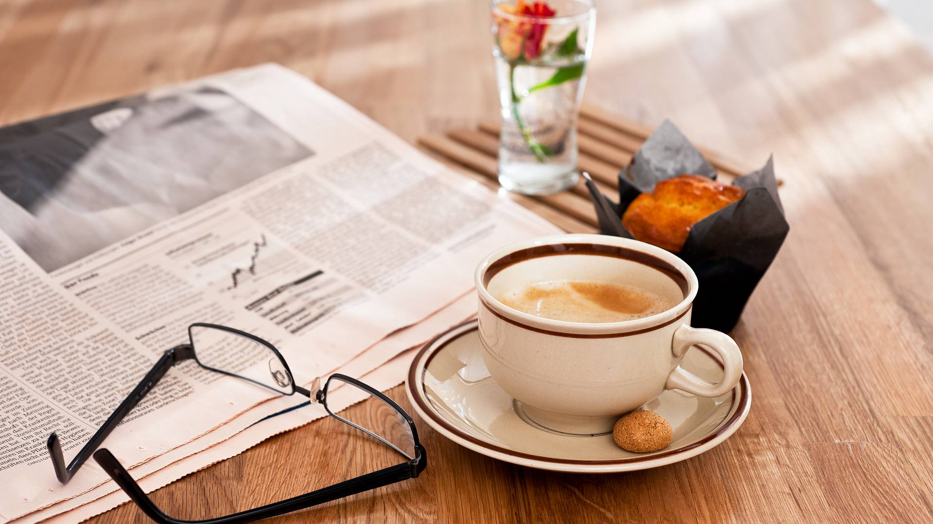 Kaffee, Frühstück und Zeitung auf einem Tisch