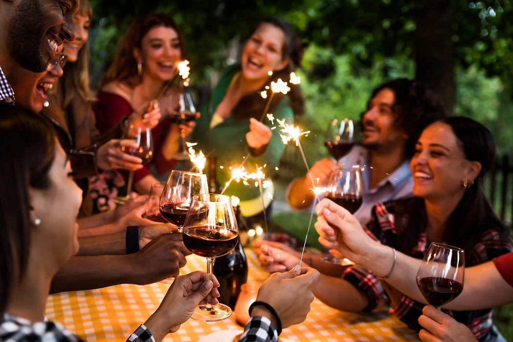 Gruppe feiert im Garten mit Wein und Wunderkerzen