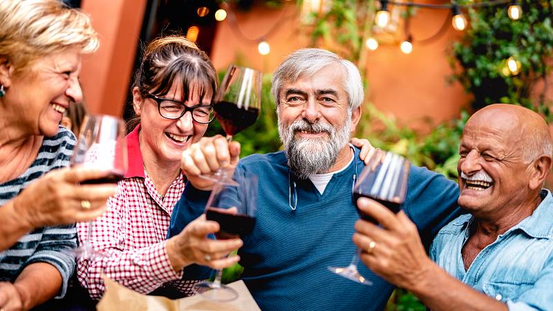 Gruppe von älteren Leuten trinkt zusammen Wein und feiert
