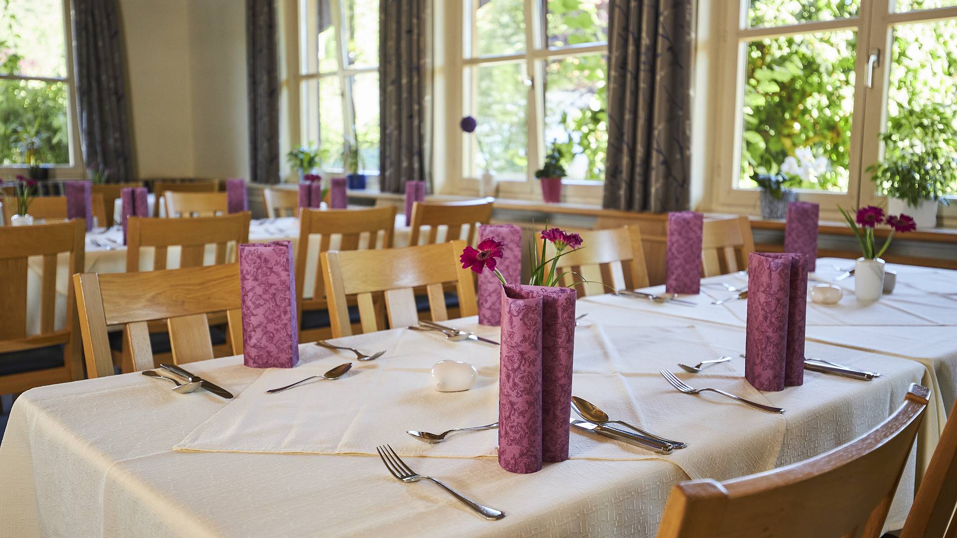 Dekorativ gedeckter Tisch mit lilafarbenen Servietten und Blumen