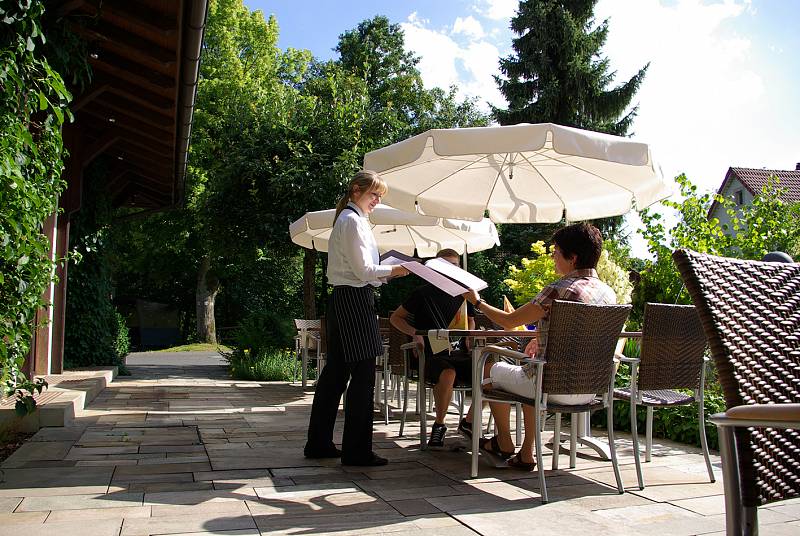 Sunny garden area with service staff showing the menu